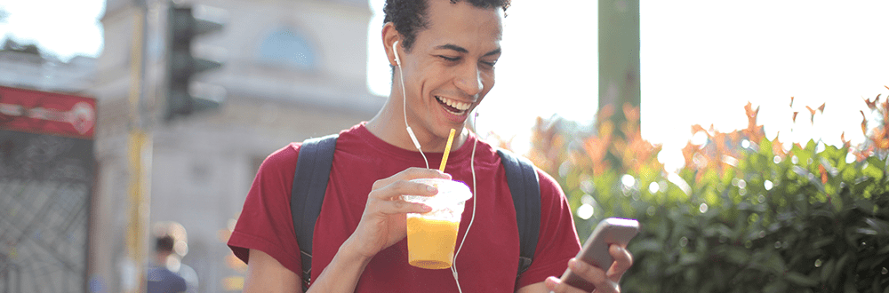 Mann mit Handy in der Hand und Getränk to go